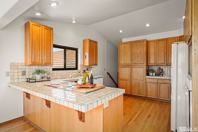 80 Cassas Ct, Reno, NV 89511 - kitchen with a peninsula, light wood-style floors, tasteful backsplash, lofted ceiling, and a kitchen bar