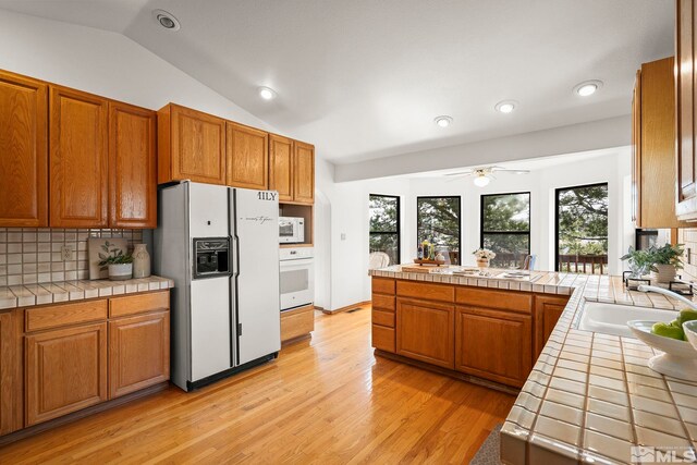 80 Cassas Ct, Reno, NV 89511 - kitchen featuring white appliances, tile counters, lofted ceiling, backsplash, and light wood-style flooring