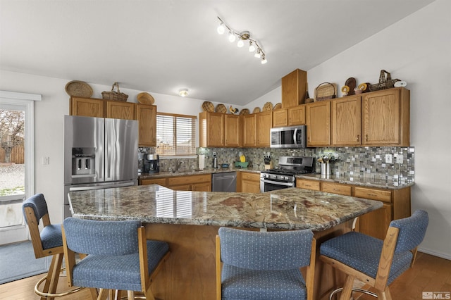 1018 Ringneck, Sparks, NV 89441 - kitchen with appliances with stainless steel finishes, a kitchen breakfast bar, light wood finished floors, backsplash, and vaulted ceiling