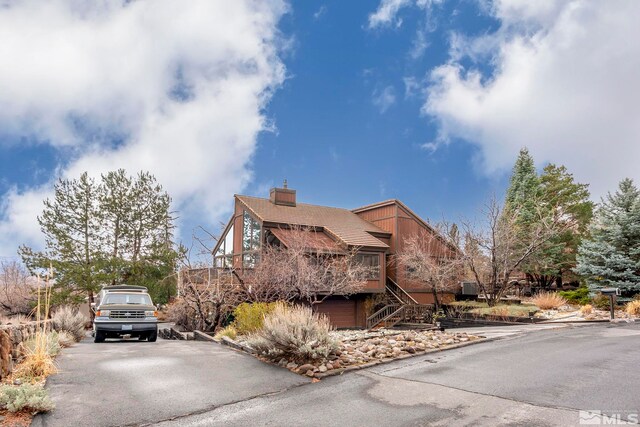 12880 Roseview Ln, Reno, NV 89511 - view of front of house with stairway, an attached garage, a chimney, and asphalt driveway