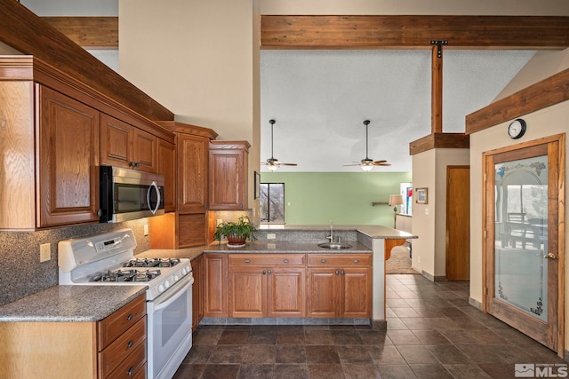 12880 Roseview Ln, Reno, NV 89511 - kitchen featuring stainless steel microwave, white range with gas stovetop, a peninsula, a sink, and decorative backsplash