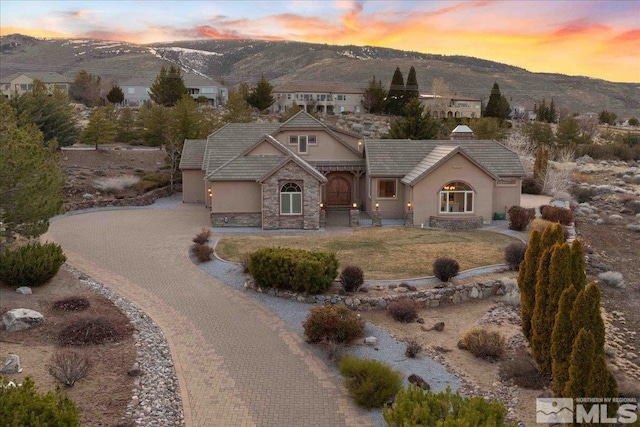 1005 Desert Jewel Ct, Reno, NV 89511 - view of front facade featuring stucco siding, a mountain view, stone siding, decorative driveway, and a tiled roof