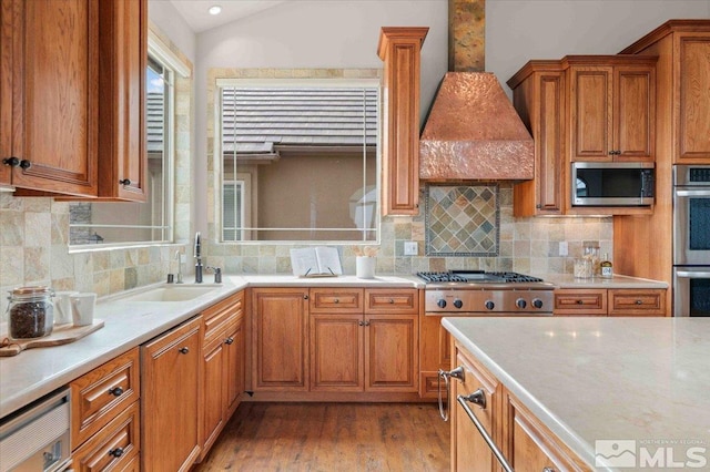 1005 Desert Jewel Ct, Reno, NV 89511 - kitchen with stainless steel appliances, a sink, custom range hood, brown cabinets, and hardwood / wood-style flooring