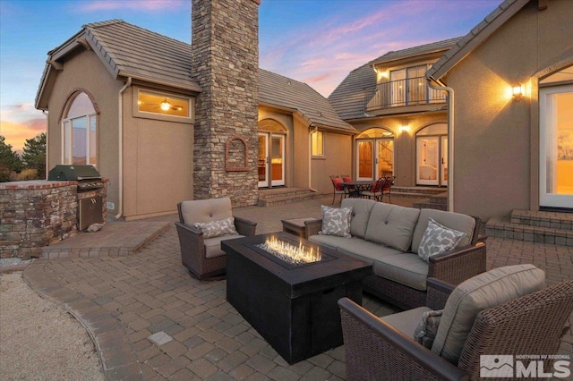 1005 Desert Jewel Ct, Reno, NV 89511 - patio terrace at dusk featuring a balcony, an outdoor living space with a fire pit, and area for grilling