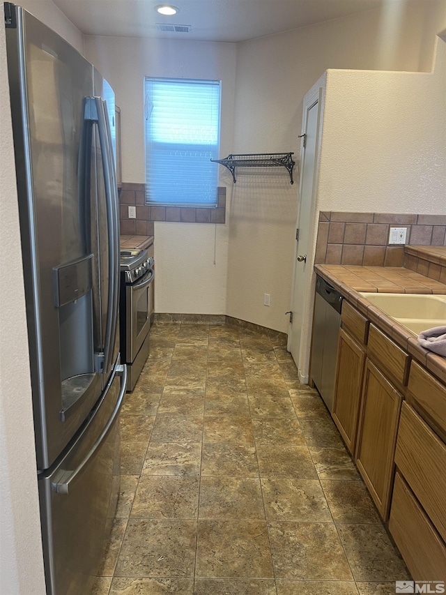 1425 Loma Verde Dr, Sparks, NV 89436 - kitchen with stainless steel appliances, tile counters, brown cabinets, and tasteful backsplash