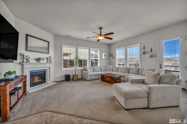 carpeted living area with a ceiling fan and a glass covered fireplace