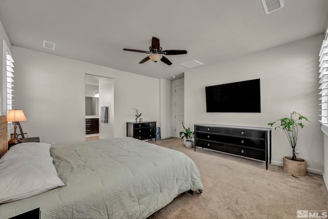 carpeted bedroom featuring ensuite bath, ceiling fan, multiple windows, and baseboards