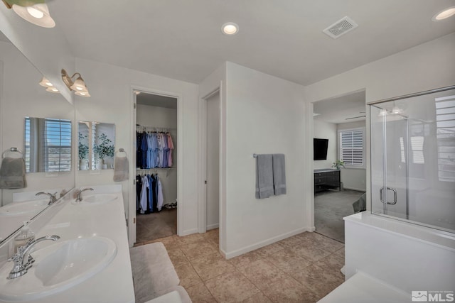 bathroom featuring a stall shower, baseboards, tile patterned floors, double vanity, and recessed lighting