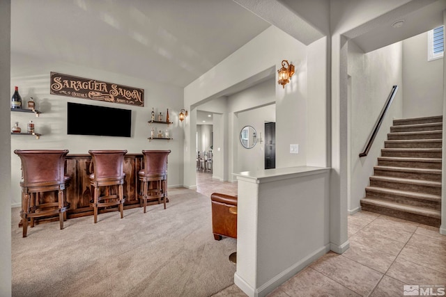 indoor dry bar with stairs, carpet flooring, baseboards, and tile patterned floors