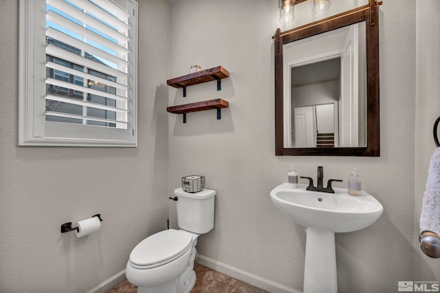 half bathroom featuring baseboards and toilet