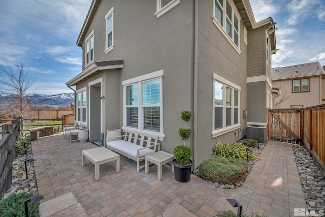 rear view of house with stucco siding, a patio, a fenced backyard, a gate, and cooling unit