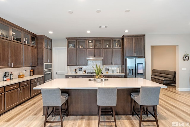 kitchen featuring appliances with stainless steel finishes, tasteful backsplash, light countertops, light wood-style flooring, and recessed lighting