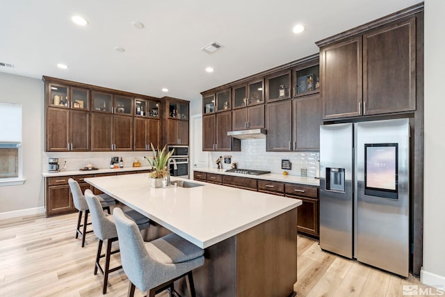 kitchen featuring stainless steel appliances, light wood-type flooring, dark brown cabinetry, light countertops, and recessed lighting