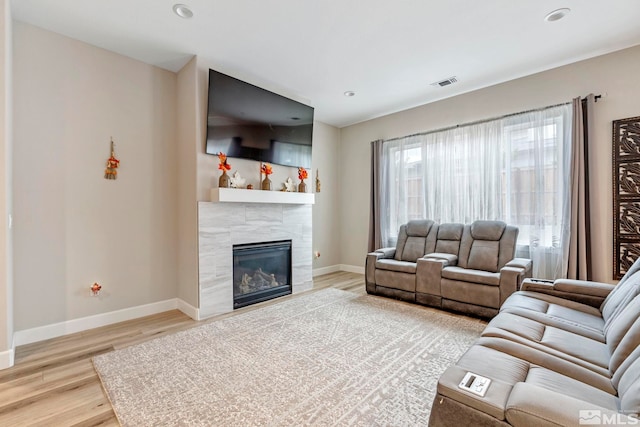 living area featuring light wood-style flooring, baseboards, a tile fireplace, and recessed lighting