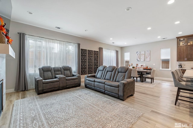 living area featuring recessed lighting, light wood-style floors, baseboards, and a tiled fireplace