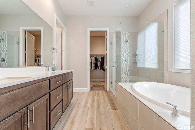 bathroom with a stall shower, a garden tub, a spacious closet, and double vanity