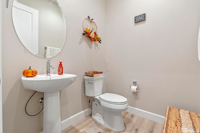 bathroom with toilet, wood finished floors, and baseboards
