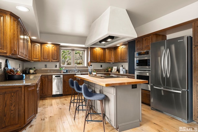 4840 Keshmiri Pl, Reno, NV 89519 - kitchen featuring appliances with stainless steel finishes, butcher block counters, custom exhaust hood, light wood finished floors, and recessed lighting