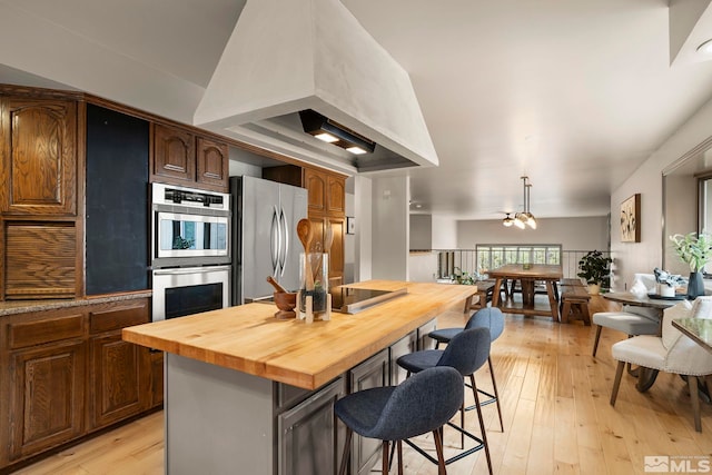 4840 Keshmiri Pl, Reno, NV 89519 - kitchen featuring stainless steel appliances, butcher block counters, a kitchen breakfast bar, light wood-style floors, and a kitchen island