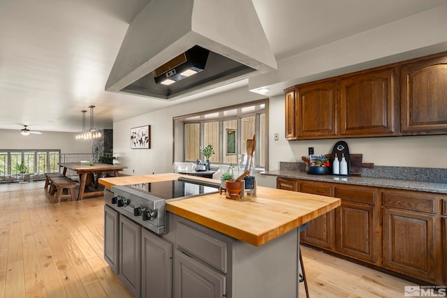 4840 Keshmiri Pl, Reno, NV 89519 - kitchen featuring butcher block countertops, custom range hood, light wood-style flooring, stainless steel cooktop, and a chandelier
