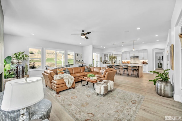 living area with light wood finished floors, ceiling fan, and recessed lighting