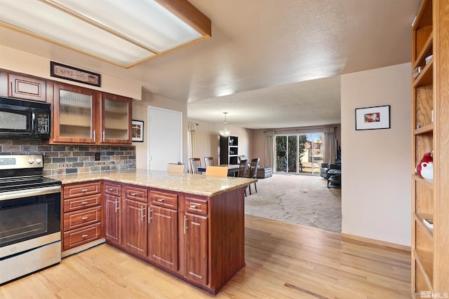 kitchen featuring black microwave, stainless steel electric stove, a peninsula, light wood-type flooring, and backsplash