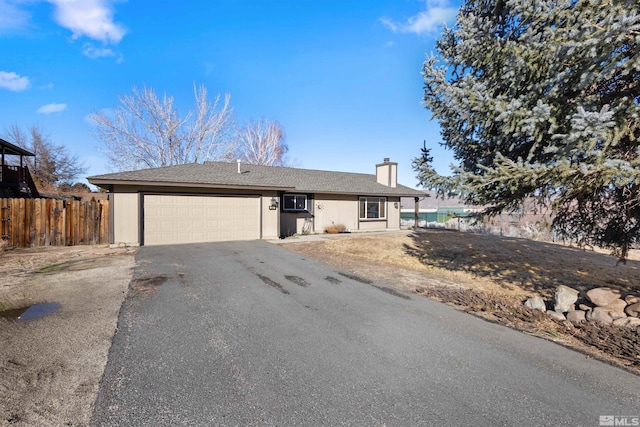 single story home featuring asphalt driveway, fence, a chimney, and a garage