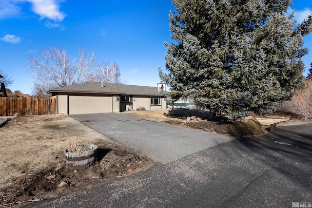 view of front of home featuring asphalt driveway, an attached garage, and fence