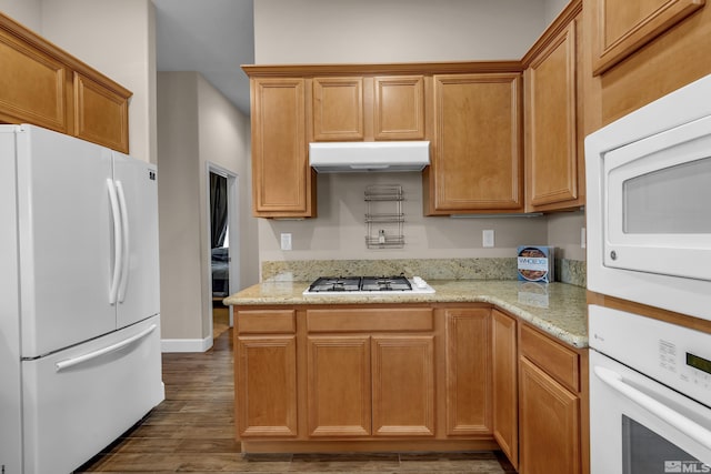 5807 Desert Mirage Dr, Sparks, NV 89436 - kitchen featuring white appliances, under cabinet range hood, dark wood-style floors, and light stone countertops
