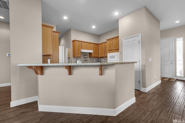 5807 Desert Mirage Dr, Sparks, NV 89436 - kitchen featuring white microwave, baseboards, under cabinet range hood, a kitchen bar, and recessed lighting