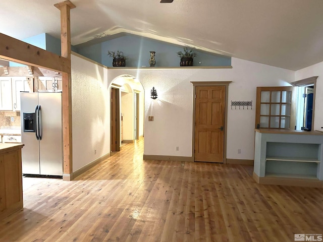 21410 Sazarac Rd, Reno, NV 89521 - unfurnished living room with vaulted ceiling, light wood-style floors, arched walkways, and baseboards