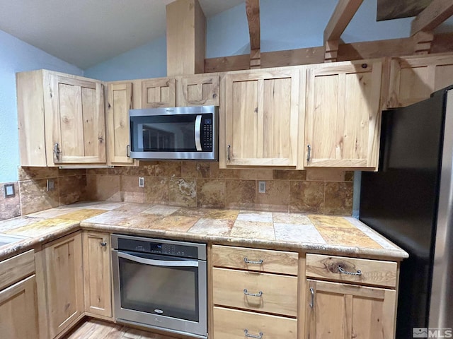 21410 Sazarac Rd, Reno, NV 89521 - kitchen featuring appliances with stainless steel finishes, light brown cabinetry, vaulted ceiling, backsplash, and tile counters