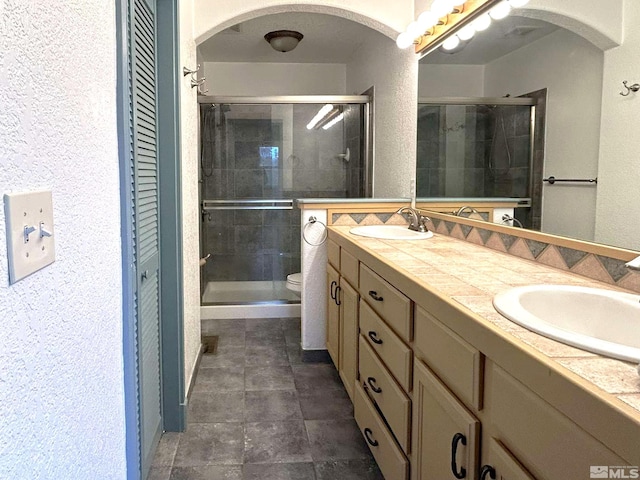 21410 Sazarac Rd, Reno, NV 89521 - bathroom with double vanity, a textured wall, a shower stall, toilet, and tile patterned flooring