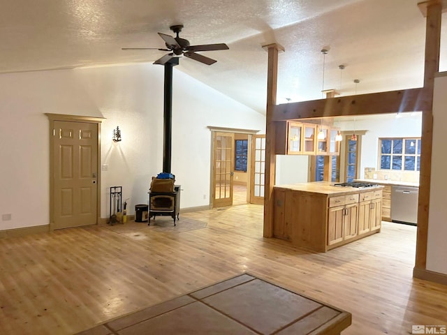 21410 Sazarac Rd, Reno, NV 89521 - living room featuring a wood stove, ceiling fan, light wood finished floors, baseboards, and high vaulted ceiling
