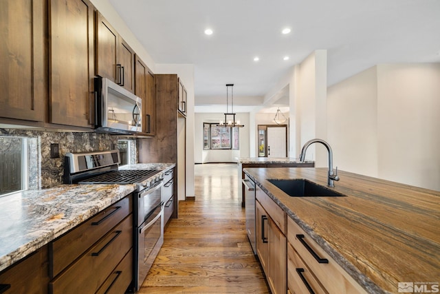 159 River Flow Dr, Reno, NV 89523 - kitchen featuring stainless steel appliances, a sink, light stone counters, light wood finished floors, and recessed lighting