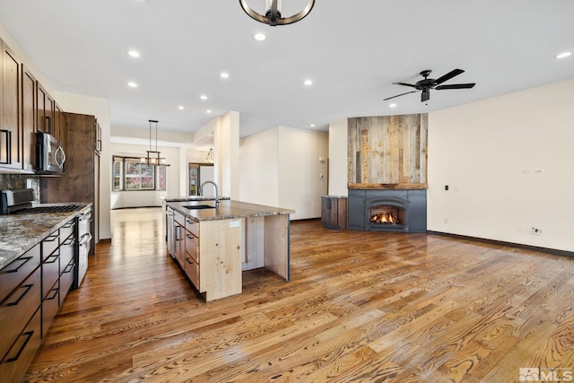 159 River Flow Dr, Reno, NV 89523 - kitchen with appliances with stainless steel finishes, a sink, light wood-style floors, dark stone counters, and open floor plan