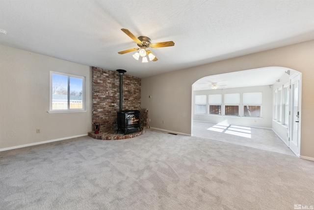 1599 Lucerne, Minden, NV 89423 - unfurnished living room featuring arched walkways, a wood stove, ceiling fan, and carpet floors