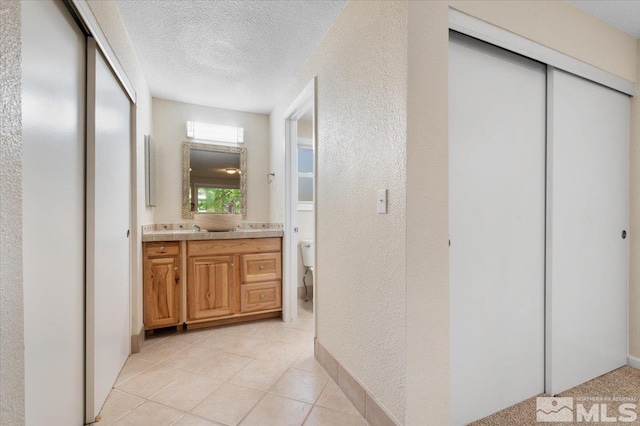 4550 Noche Ln, Reno, NV 89502 - bathroom featuring toilet, a textured ceiling, vanity, a textured wall, and tile patterned flooring