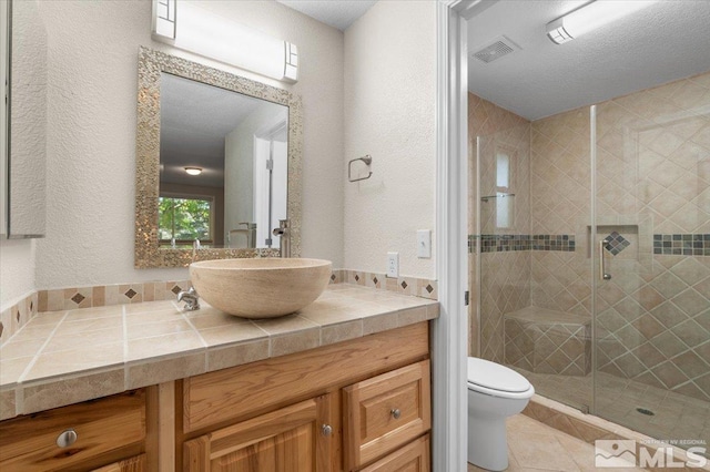 4550 Noche Ln, Reno, NV 89502 - bathroom featuring a stall shower, toilet, vanity, a textured wall, and tile patterned floors
