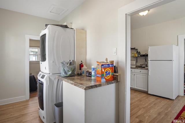 529 11th St, Sparks, NV 89431 - kitchen with freestanding refrigerator, stacked washer / dryer, light wood-style flooring, dark countertops, and baseboards