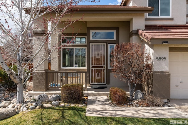 5895 Tappan Dr, Reno, NV 89523 - view of exterior entry with stucco siding, a garage, and covered porch