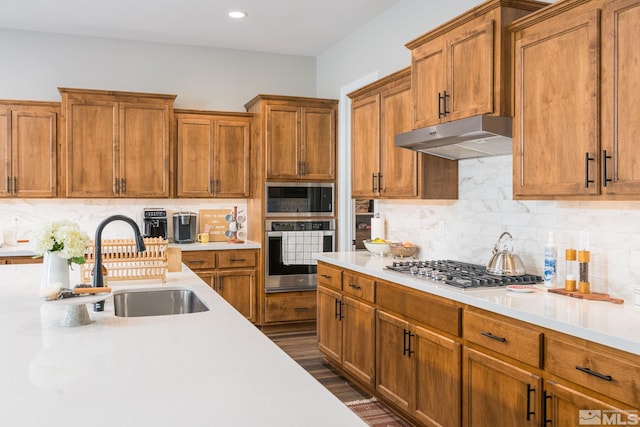 kitchen with appliances with stainless steel finishes, under cabinet range hood, light countertops, backsplash, and recessed lighting