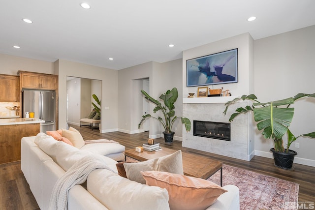 living room featuring a glass covered fireplace, recessed lighting, dark wood finished floors, and baseboards