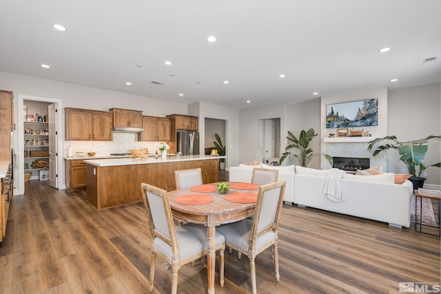 dining space featuring dark wood-style flooring, recessed lighting, and a glass covered fireplace