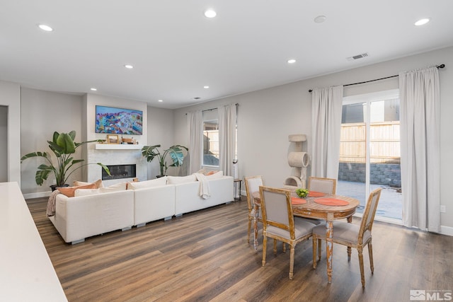 dining room with plenty of natural light, wood finished floors, recessed lighting, and a glass covered fireplace