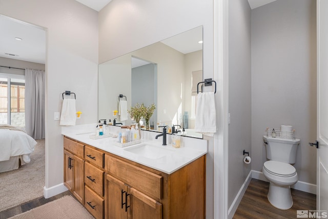 full bathroom with wood finished floors, double vanity, connected bathroom, and toilet
