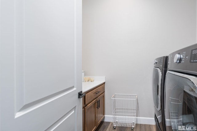 clothes washing area featuring washing machine and clothes dryer, dark wood-style flooring, cabinet space, and baseboards