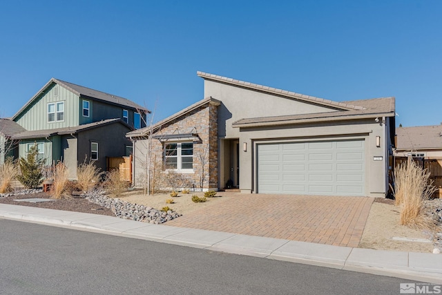 view of front of house with an attached garage, decorative driveway, stucco siding, and stone siding