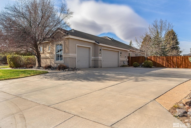 7972 Tres Arroyos Dr, Sparks, NV 89436 - view of property exterior featuring an attached garage, fence, driveway, and stucco siding
