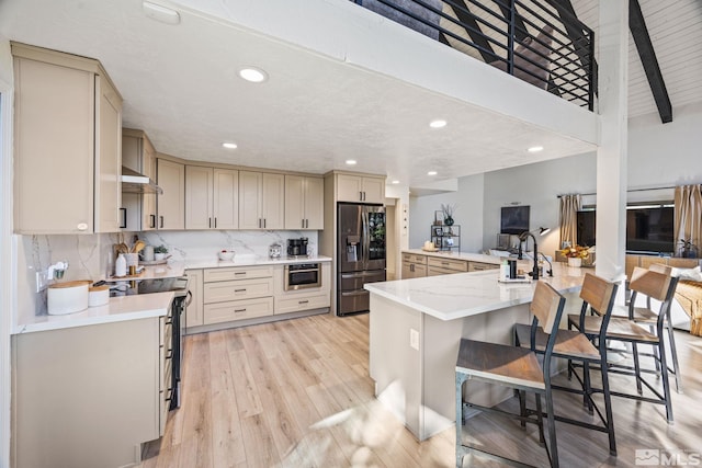 3055 US Highway 395, Washoe Valley, NV 89704 - kitchen featuring stainless steel refrigerator with ice dispenser, range with electric cooktop, a kitchen breakfast bar, cream cabinets, and light wood-style floors